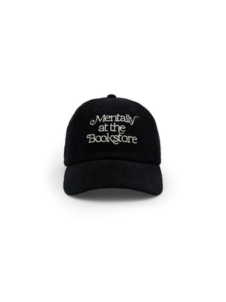 A black corduroy baseball cap with the phrase 'Mentally at the Bookstore' embroidered on the front.