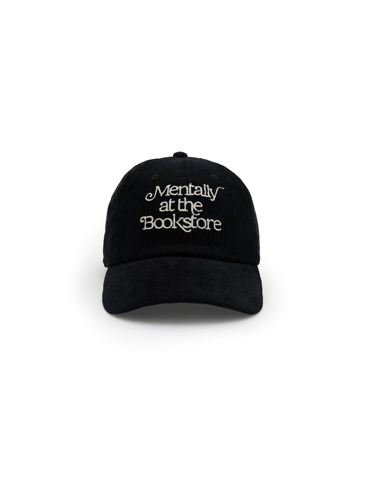 A black corduroy baseball cap with the phrase 'Mentally at the Bookstore' embroidered on the front.