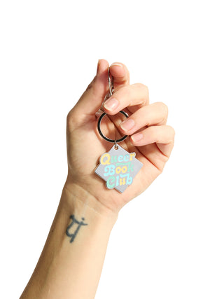 Hand holding a keychain with a colorful geometric design on a white background