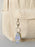 Keychain with a teardrop design attached to a beige corduroy bag.