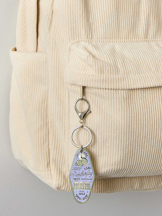 Keychain with a teardrop design attached to a beige corduroy bag.
