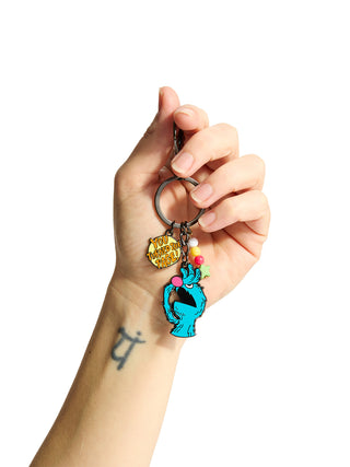 Hand holding a keychain with colorful charms against a white background