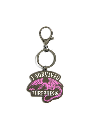 Keychain with dragon design and text 'I Survived Threshing' on a white background