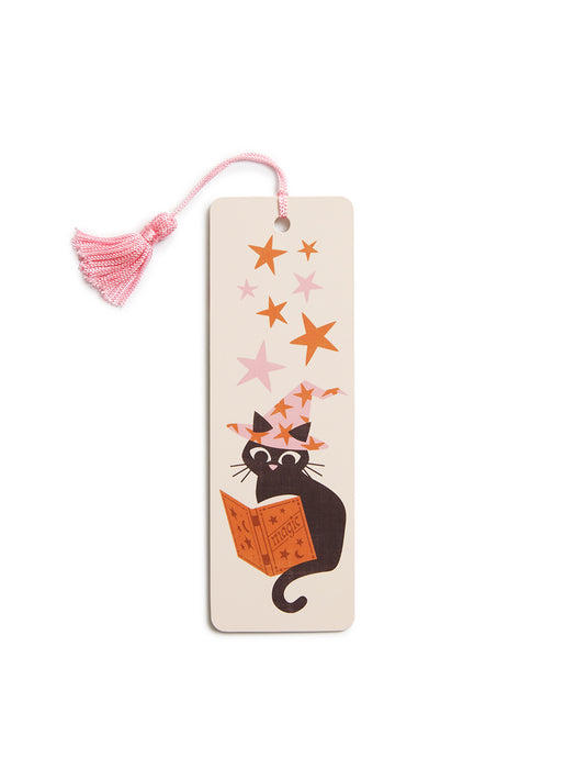 A rectangular cream-colored paper bookmark with a pink tassel, featuring a black cat reading an orange book under pink and orange stars.