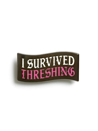 Enamel pin with 'I Survived Threshing' text on a white background