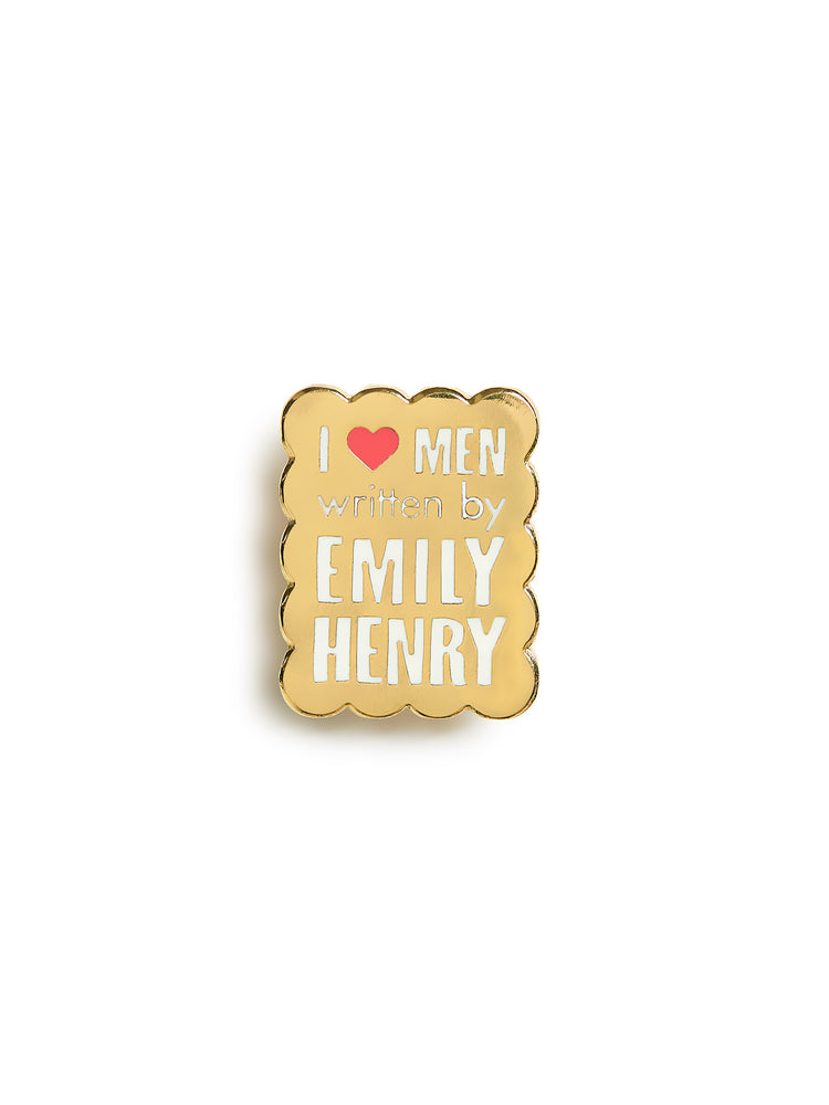 Gold enamel pin with text 'I ❤️ MEN written by EMILY HENRY' on a white background