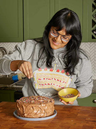 Woman decorating a cake in a kitchen