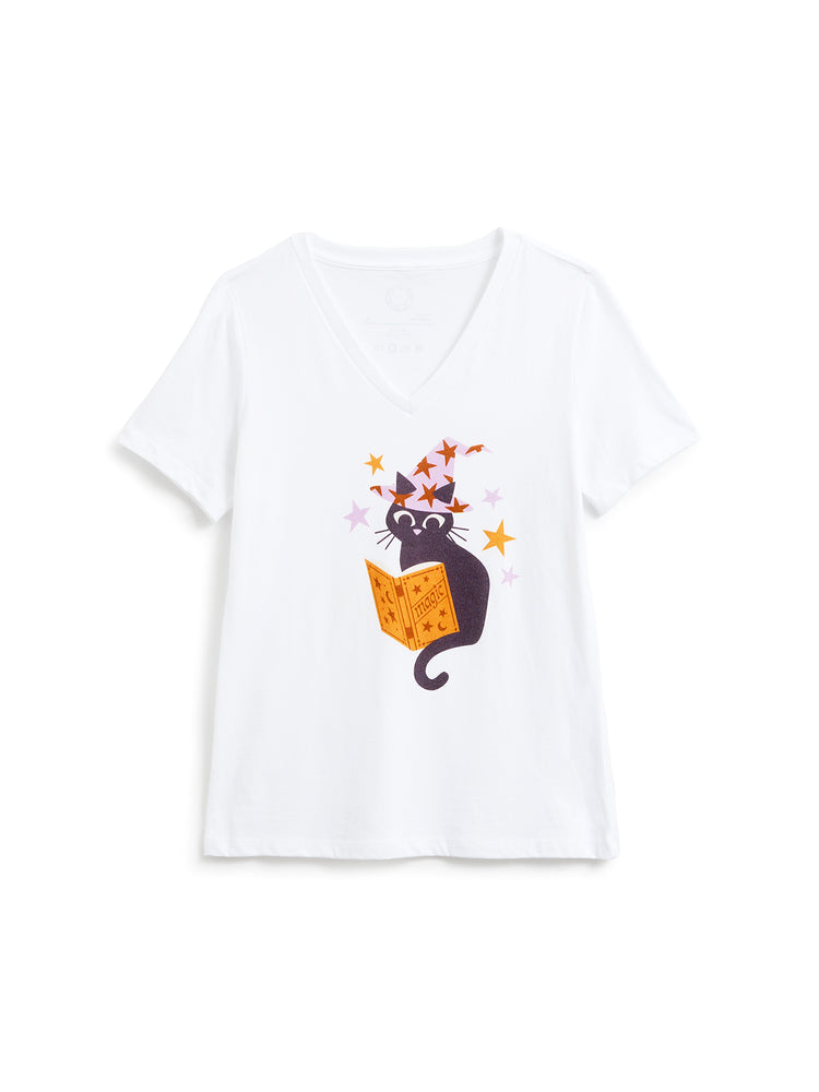 A white short-sleeve V-neck t-shirt featuring a cartoon graphic of a black cat reading an orange spellbook with colorful stars, displayed on a clean white background.