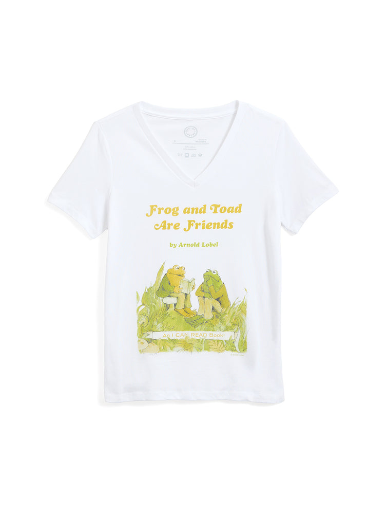 A white short-sleeve V-neck t-shirt featuring a graphic print of the classic 'Frog and Toad Are Friends' book cover, including the title in yellow text and an illustration of the characters on a green grassy field.