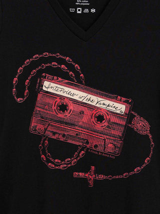 A close-up of a black v-neck t-shirt featuring a graphic print of a red cassette tape necklace with a rosary and cross, with the handwritten text 'Interview w/ the Vampire' on the cassette.