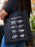 Black tote bag with white knot designs and 'BRIDE' text held by a person.