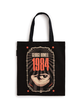 A black canvas tote bag featuring a graphic print of the book cover for George Orwell's 1984. The design includes the title '1984' in bold red-orange text, an eye illustration, and decorative borders, with 'GEORGE ORWELL' printed above.