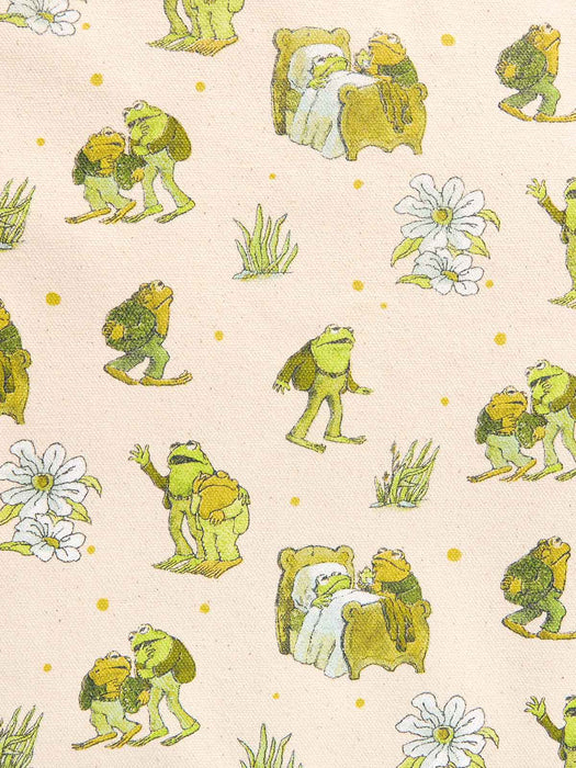 A close-up of a fabric pattern featuring green and yellow frogs, white flowers, and small yellow dots on a light beige background.