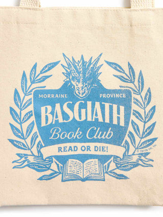 A cream canvas tote bag featuring a blue graphic print of a dragon head, laurel wreath, and an open book with the text 'BASGIATH Book Club' and 'READ OR DIE!'.