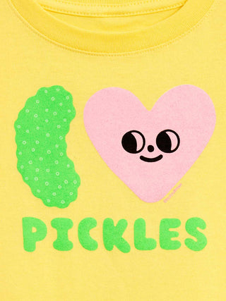 Close-up of a yellow t-shirt featuring a pink heart with a smiling face, a green pickle graphic, and the word 'PICKLES' in green letters.