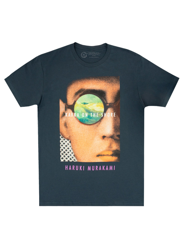 A navy-colored unisex t-shirt featuring a graphic of a person's face with a green eye, text, and a reference to the book 'Kafka on the Shore' by Haruki Murakami.