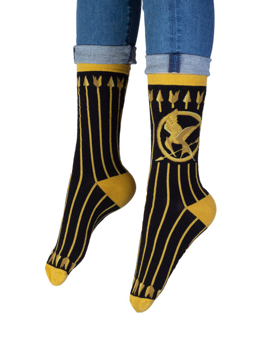 A pair of black and gold Hunger Games-themed socks featuring the Mockingjay symbol.