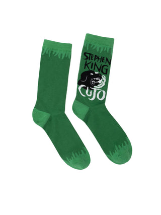 A pair of green socks with the text 'Stephen King Cujo' printed on the upper part, along with a graphic that resembles a werewolf or monster.