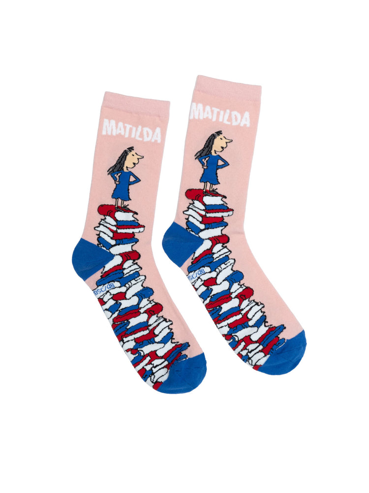 A pair of pink socks with an illustration of a character standing on a stack of books, with the name 'Matilda' written across the top.